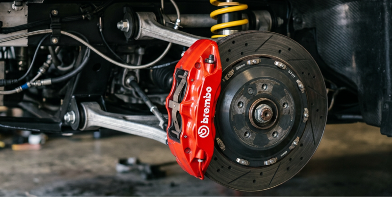 Car suspension and brake assembly with red Brembo caliper and yellow coil spring-1