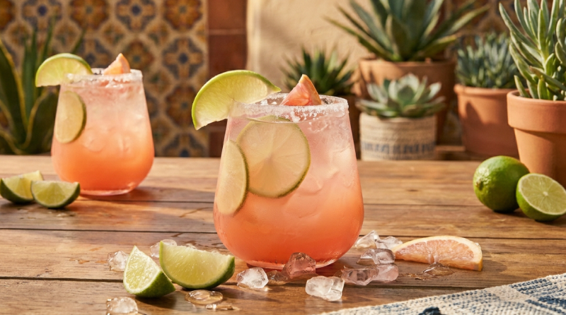 Two paloma cocktails with lime and grapefruit on a courtyard table
