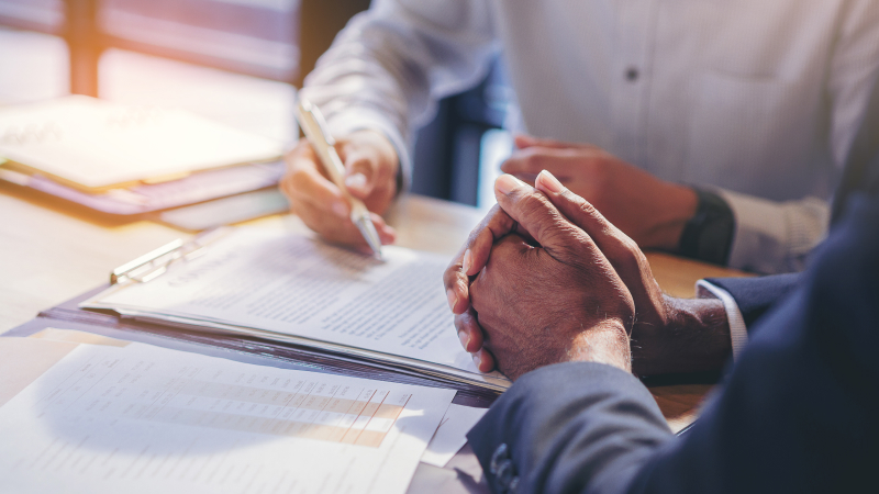 Two people review and sign paperwork at a desk