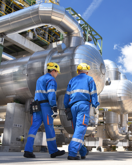 Two workers inspect industrial piping and equipment at a processing plant-1