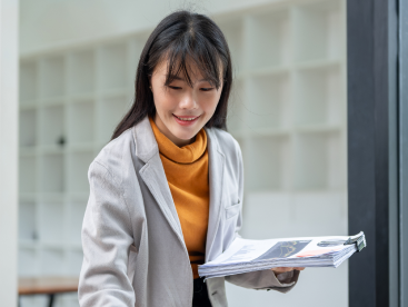 Colleague holding reports while working at a laptop in an office-1