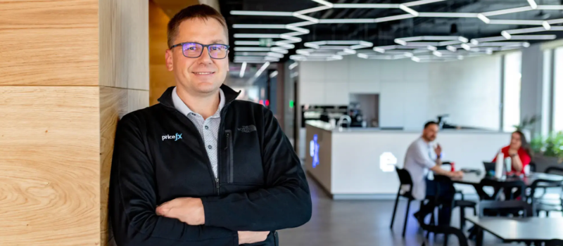 Colleague standing in a Pricefx office with coworkers in the background