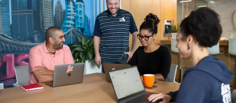Colleagues collaborating around laptops in a meeting room