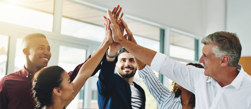Colleagues high-fiving in an office, suggesting teamwork and shared success1
