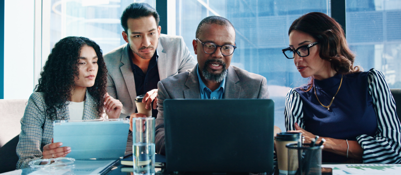 Four colleagues reviewing a laptop and tablet in a meeting room1