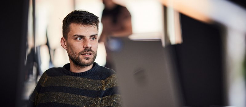 Employee speaking with a colleague from a workstation