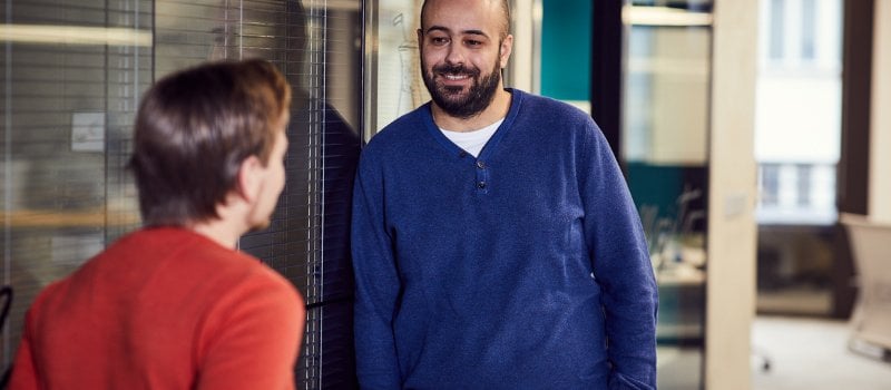 Two colleagues talking in an office corridor