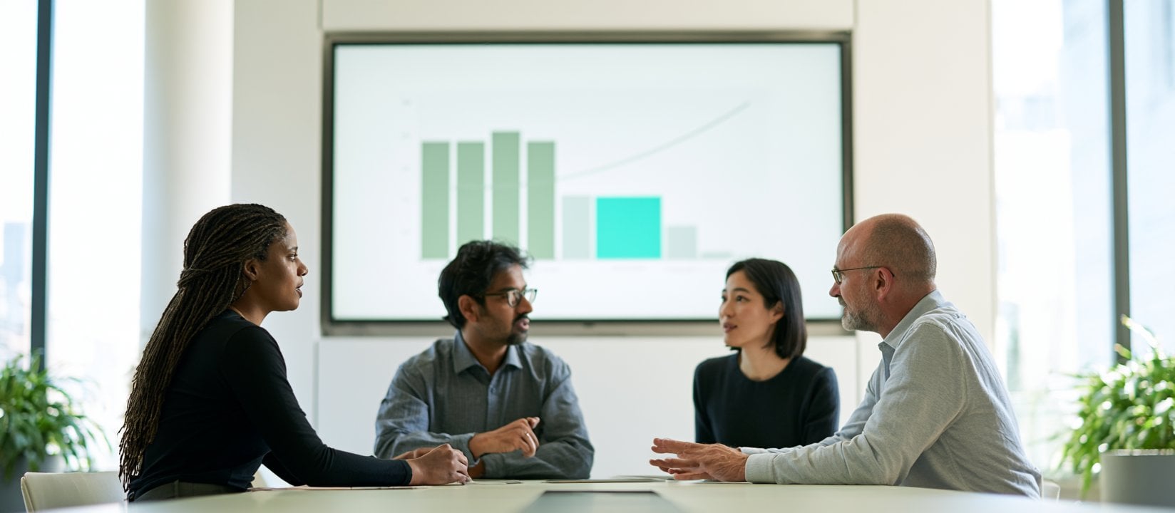 Four colleagues discuss performance trends around a conference table