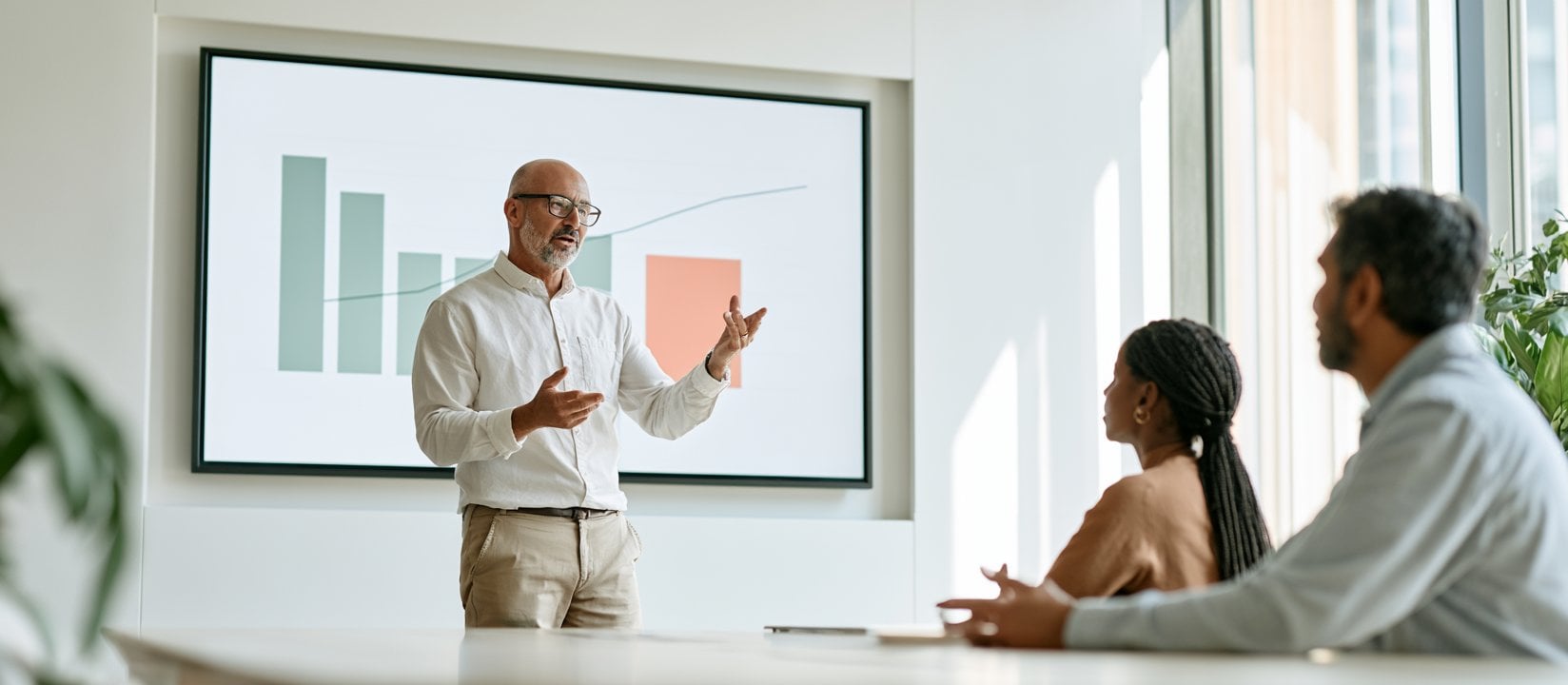 Presenter explains chart results to two teammates in a meeting room