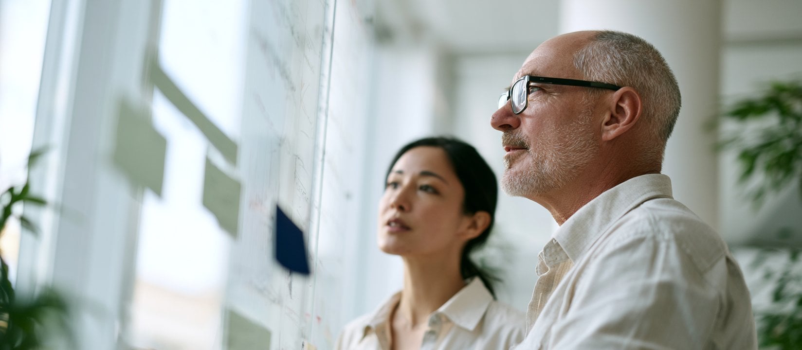 Two colleagues study a planning board covered with notes