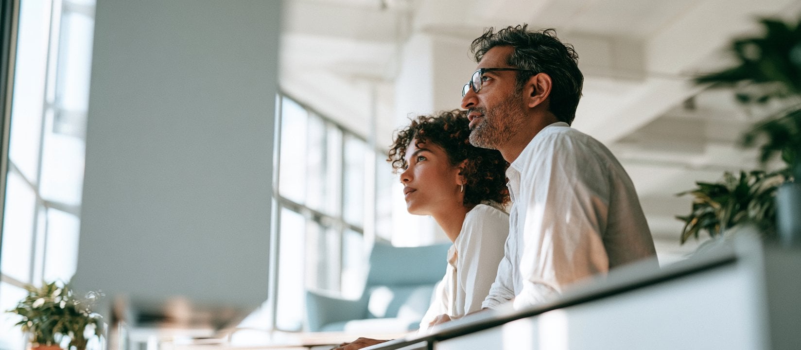 Two coworkers focus on a presentation in a sunlit office