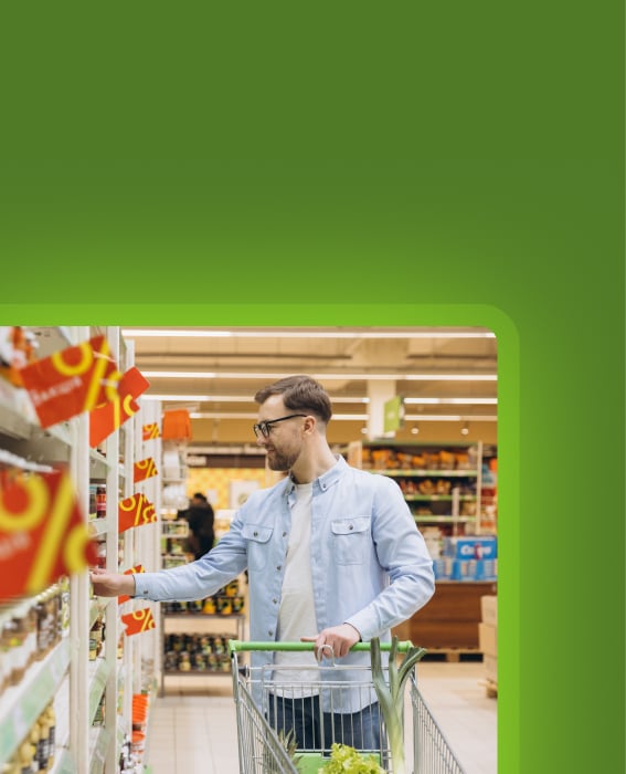 Shopper selecting a product from a grocery shelf with a cart