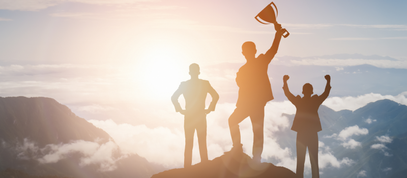 Team celebrates on a summit, one person raising a trophy1