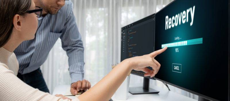 Two colleagues monitor Recovery screen showing loading progress-1