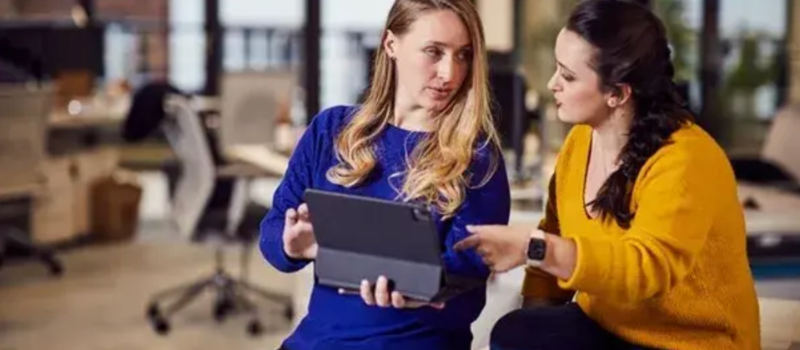 Two colleagues reviewing a tablet together in an office