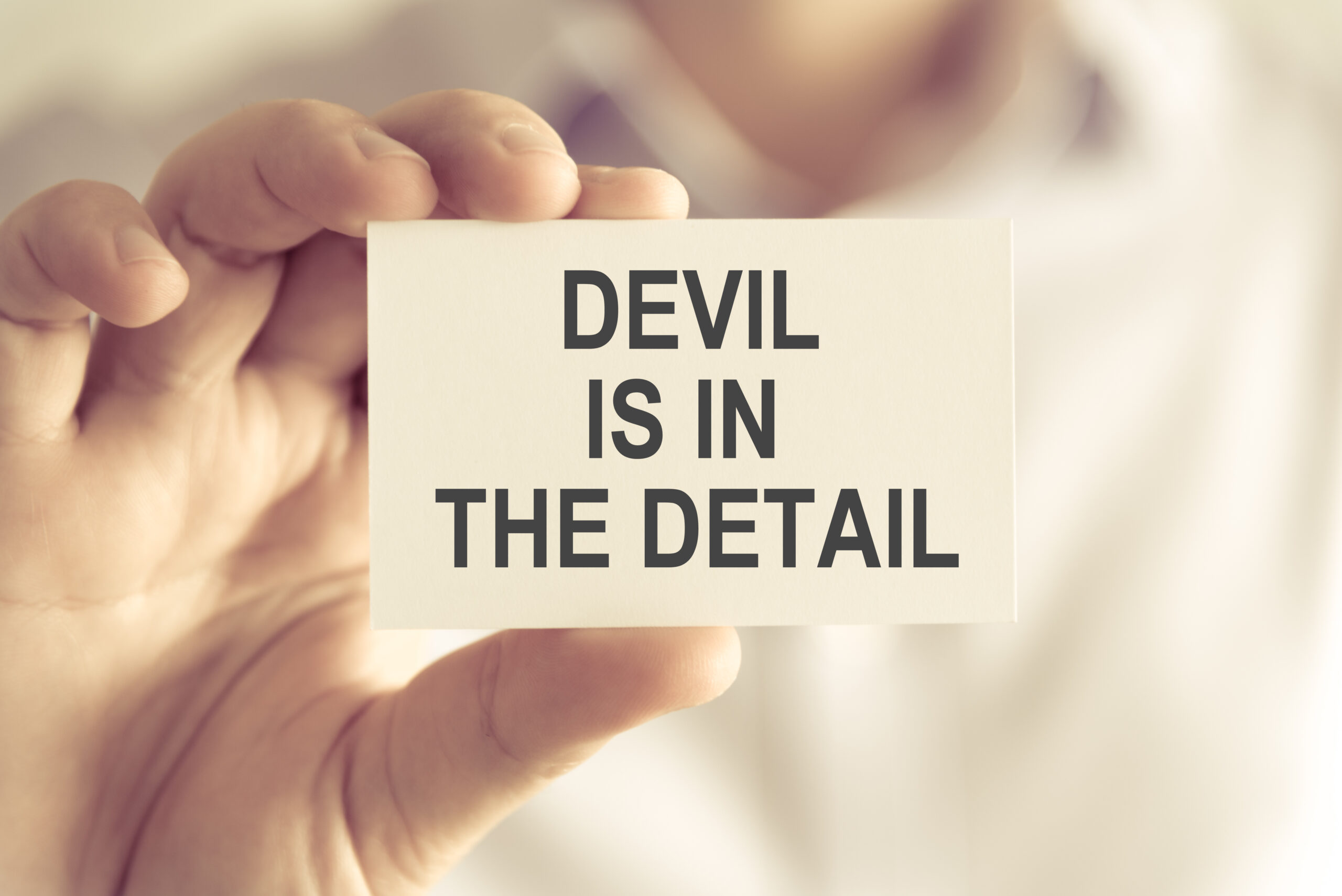 Devil-Is-In-The-Detail-Business-Card-Held-Between-Fingers