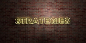 Strategies-Yellow-Neon-Sign-Set-Against-A-Brick-Wall