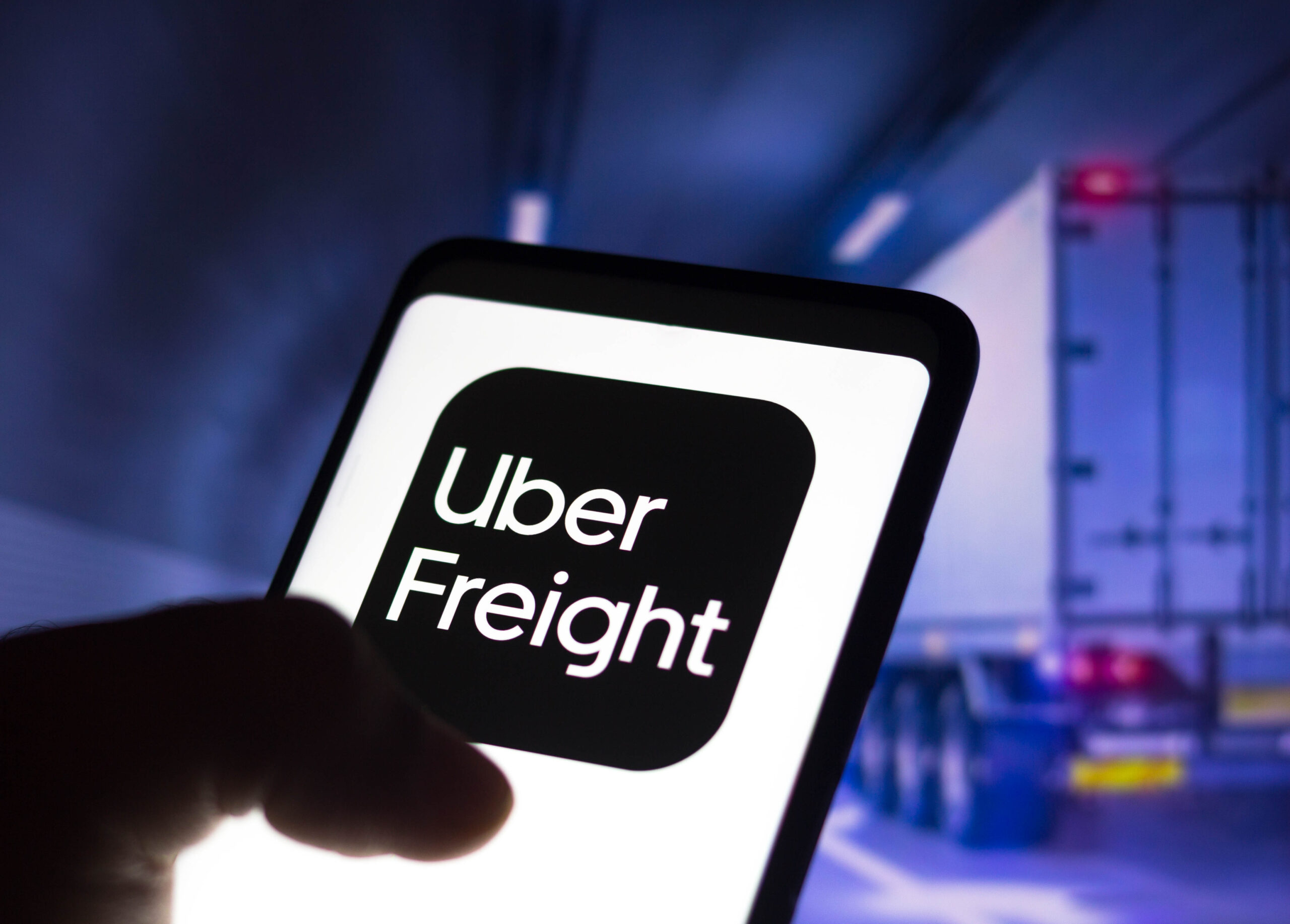 Uber-Freight-App-on-smartphone-with-delivery-truck-in-the-background